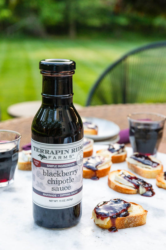a bottle of black liquid next to a plate of bread with jam
