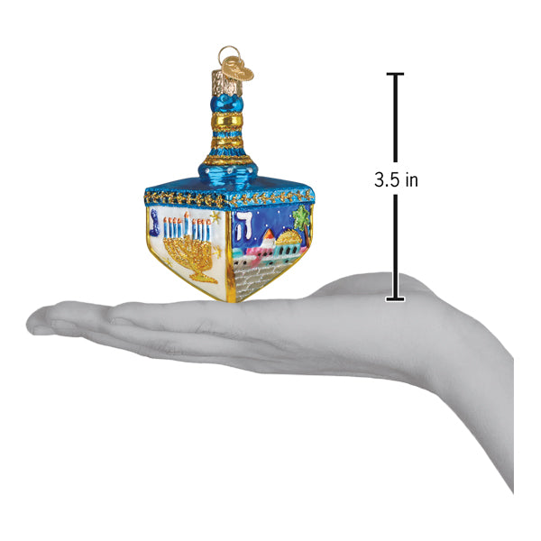 a hand holding a blue and gold decorated christmas ornament