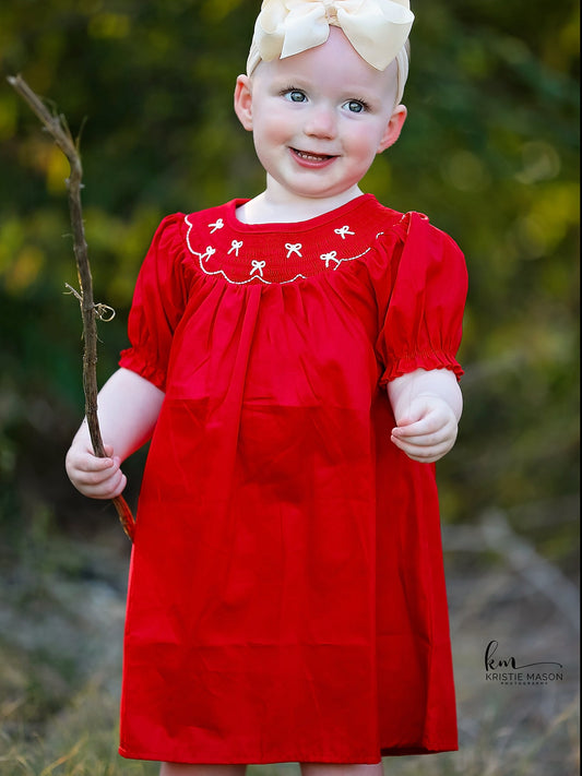 a child in a red dress holding a stick