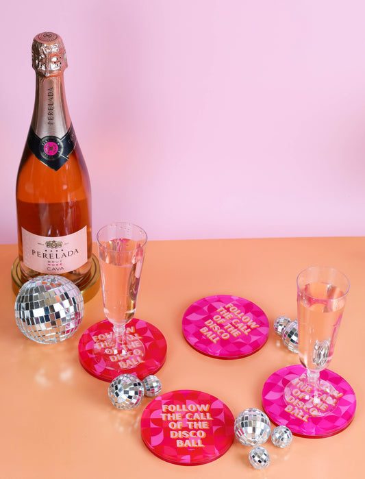 a bottle of champagne next to a pair of pink coasters