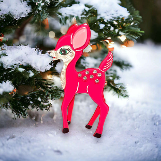 a pink deer ornament on a snowy tree