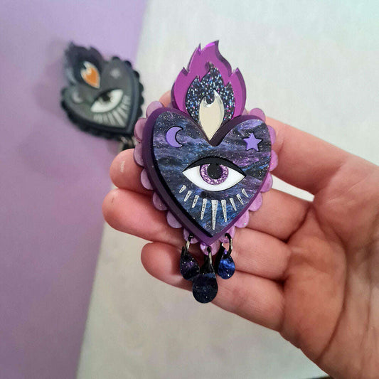 a hand holding a purple heart with a eye and fire