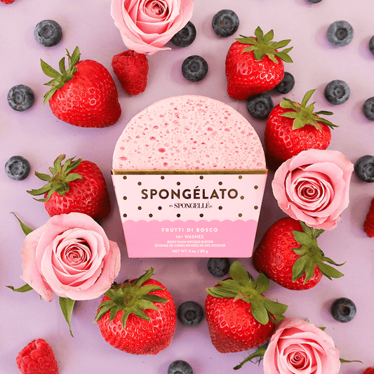 a pink sponge surrounded by strawberries and roses