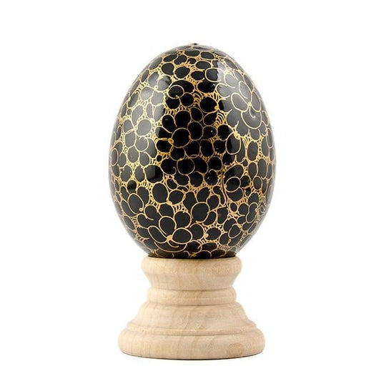 a black and gold egg on a wooden stand
