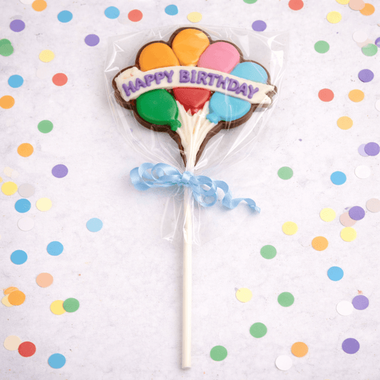 a cookie in a shape of a flower with balloons on a stick
