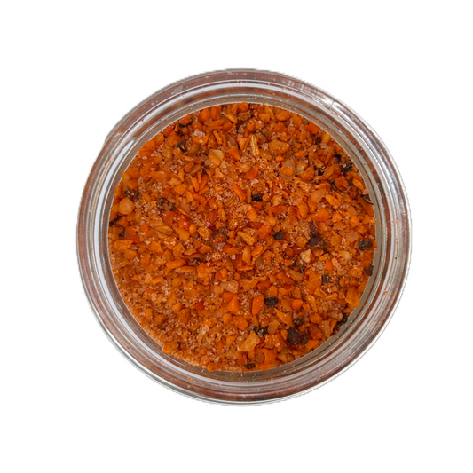a glass container with orange and black spices