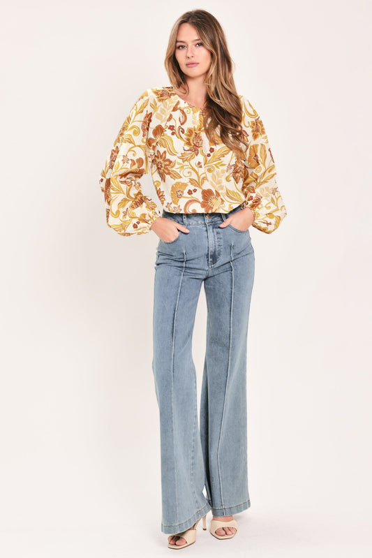 a woman in a yellow floral shirt and blue jeans
