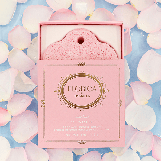 a pink bath sponge in a box on a blue surface with white petals