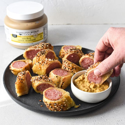 a hand dipping a sausage roll into a pastry