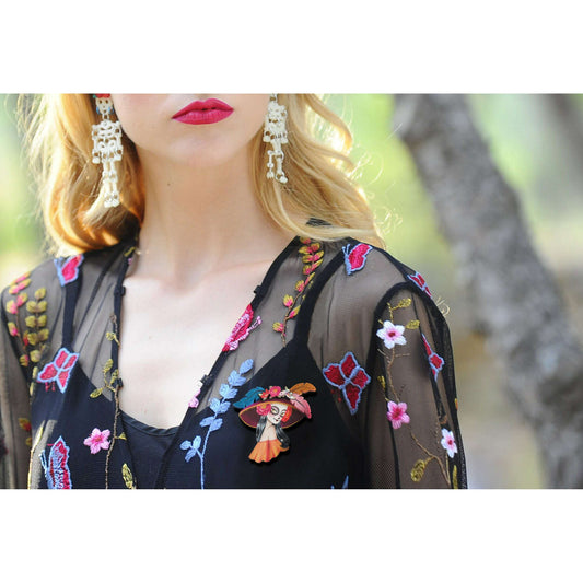 a woman wearing a black dress with flowers and earrings