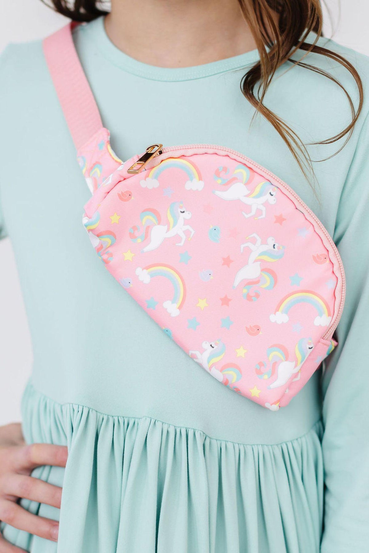 a girl wearing a pink bag with unicorns and rainbows