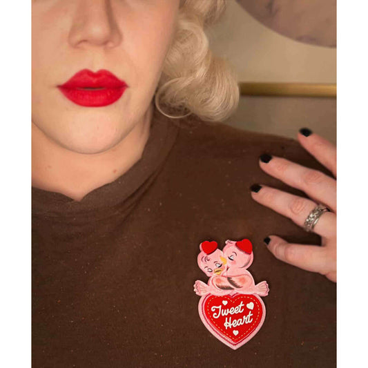 a woman with red lips and a heart pin