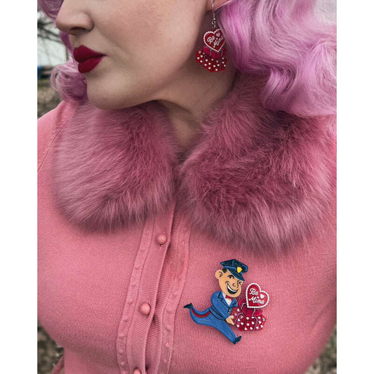 a woman wearing a pink sweater with a cartoon pin on her chest
