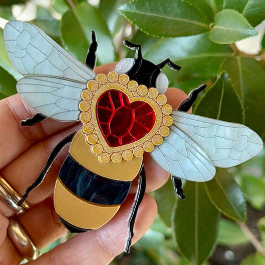 a hand holding a bee brooch