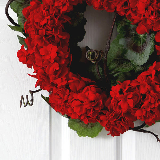 a wreath of red flowers on a white door