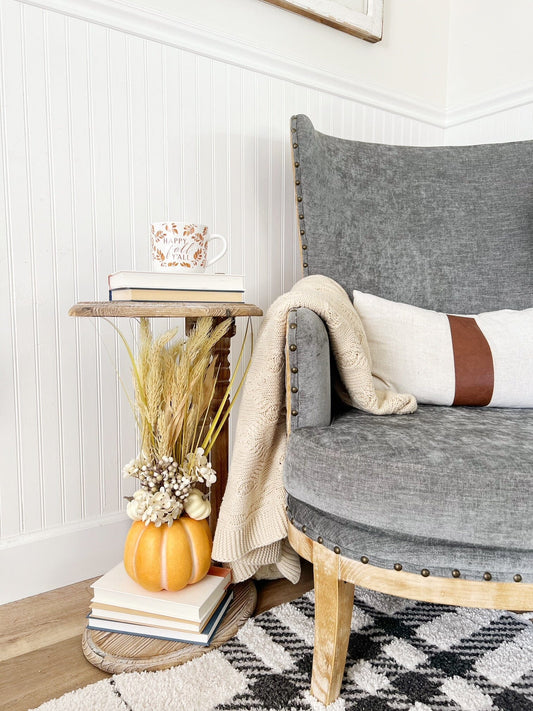 a chair with a pumpkin and a mug on top of a table