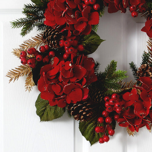 a wreath with red flowers and pine cones