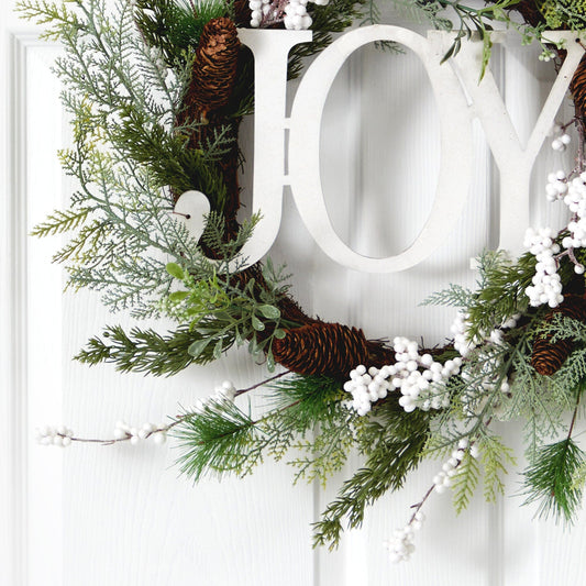 a wreath with pine cones and berries on a door