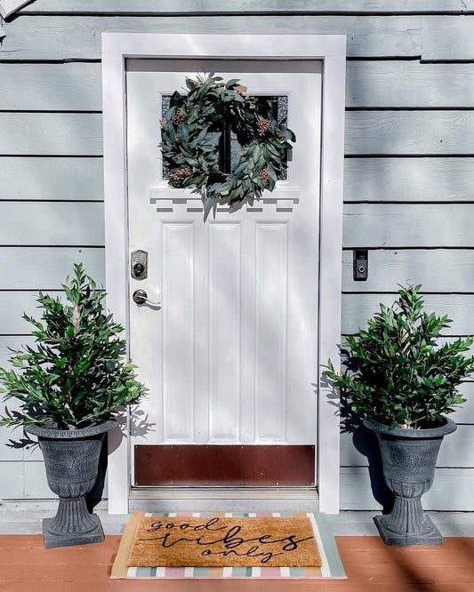 a door with a wreath and two potted plants