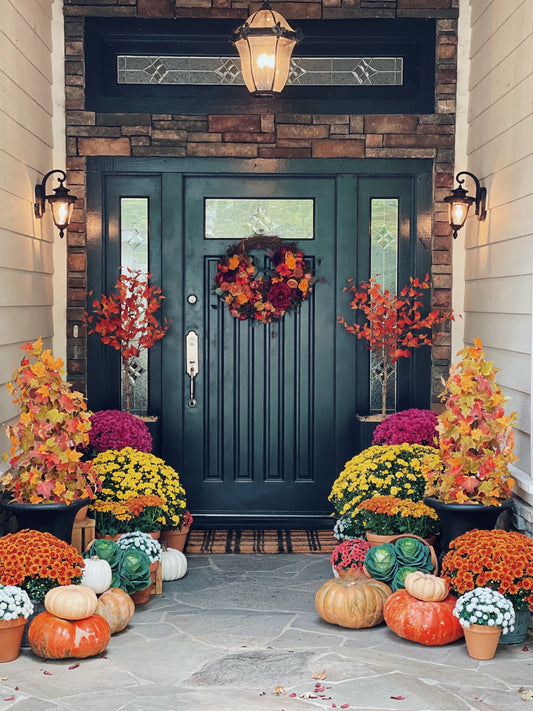 a front door with pumpkins and flowers