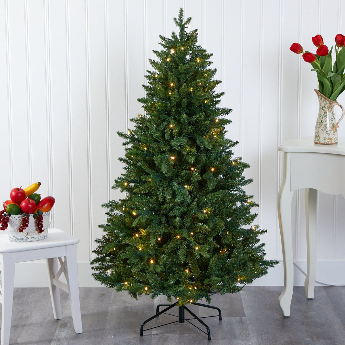 a christmas tree with lights and flowers in a vase