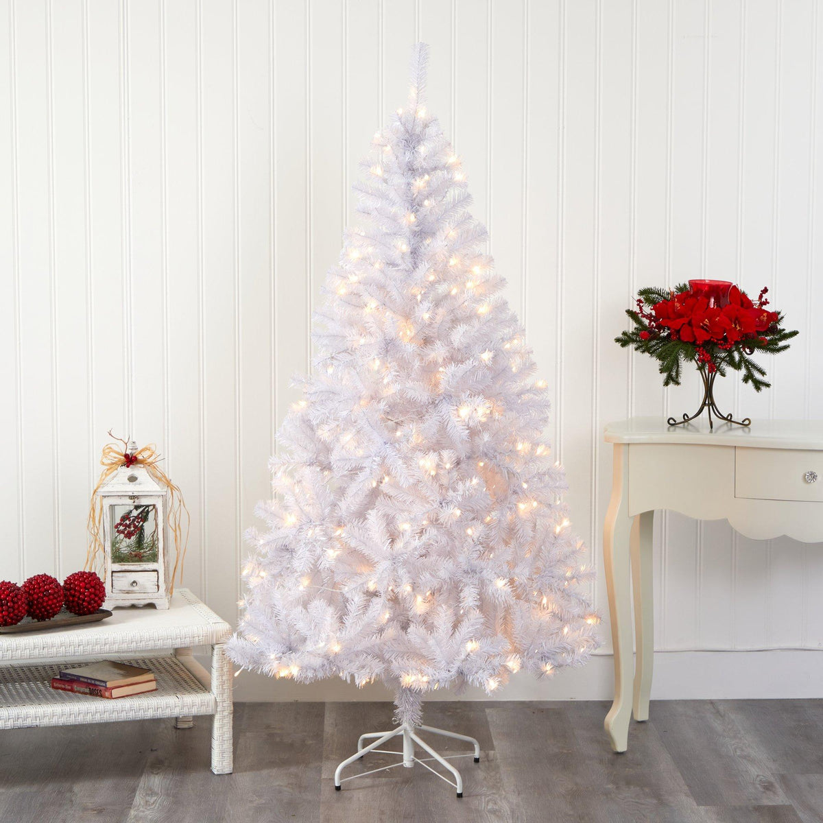 a white christmas tree with lights and a table with red balls