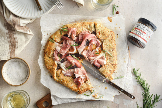 a pizza with meat and herbs on a white paper