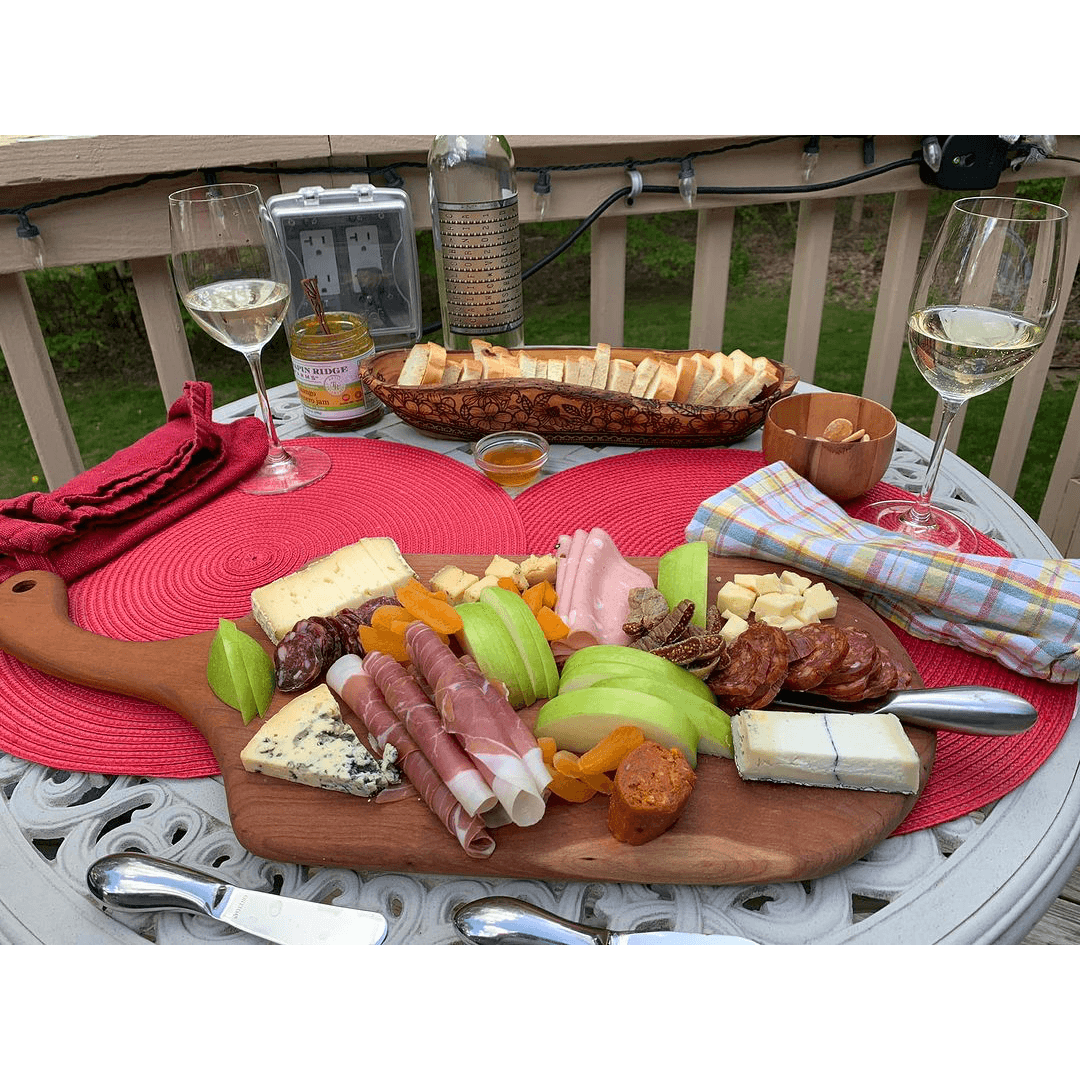 a board with meat and cheese on a table with wine glasses