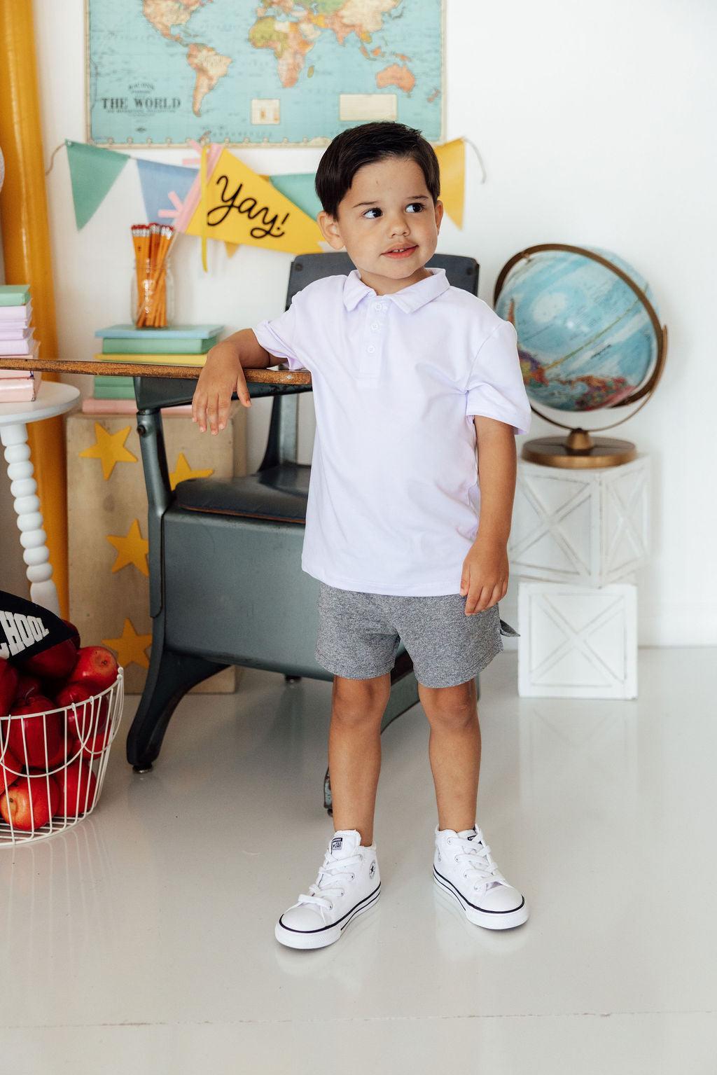 a boy standing in front of a desk