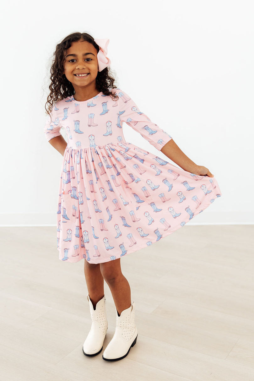 a girl wearing a pink dress and cowboy boots