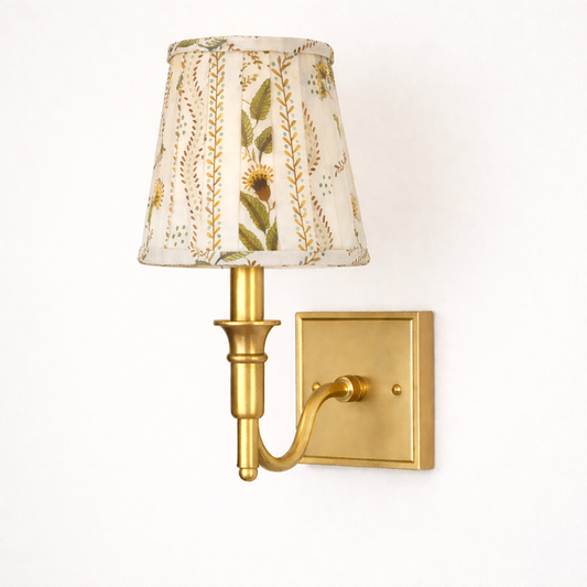 a gold wall lamp with a white shade