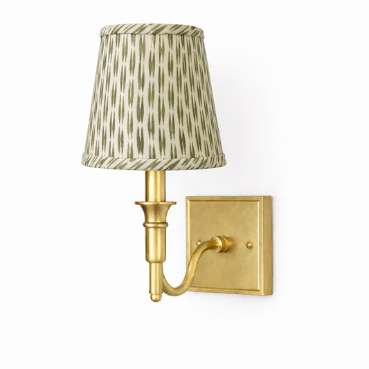 a gold wall lamp with a green shade