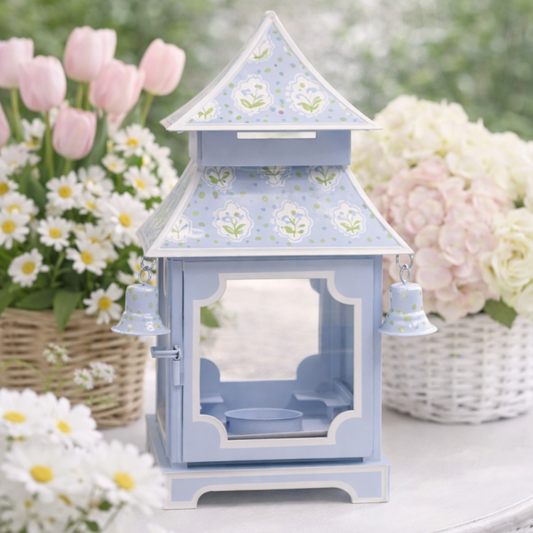 a blue lantern with bells and flowers in front of it