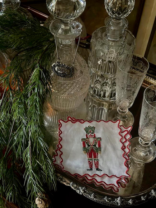 a glass decanter and glasses with a napkin and pine branch