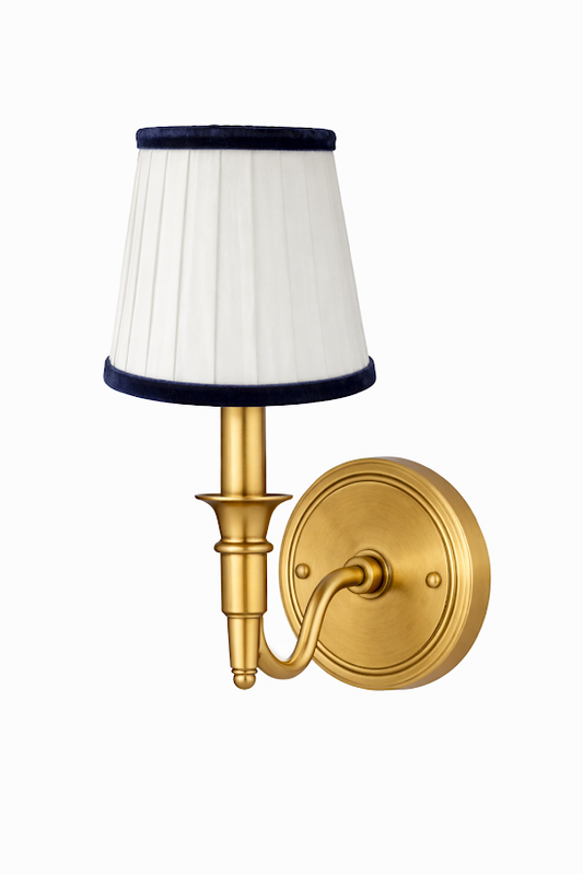 a gold wall lamp with a white shade