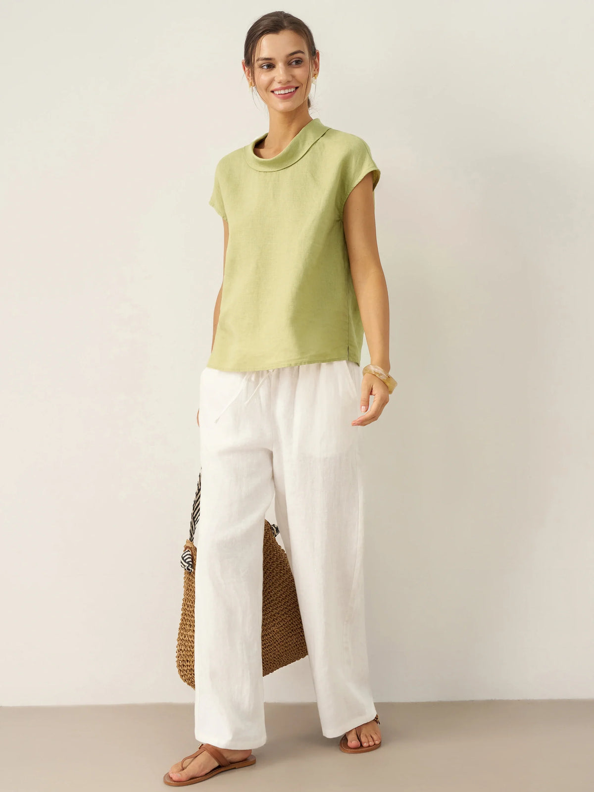 a woman in a green shirt and white pants