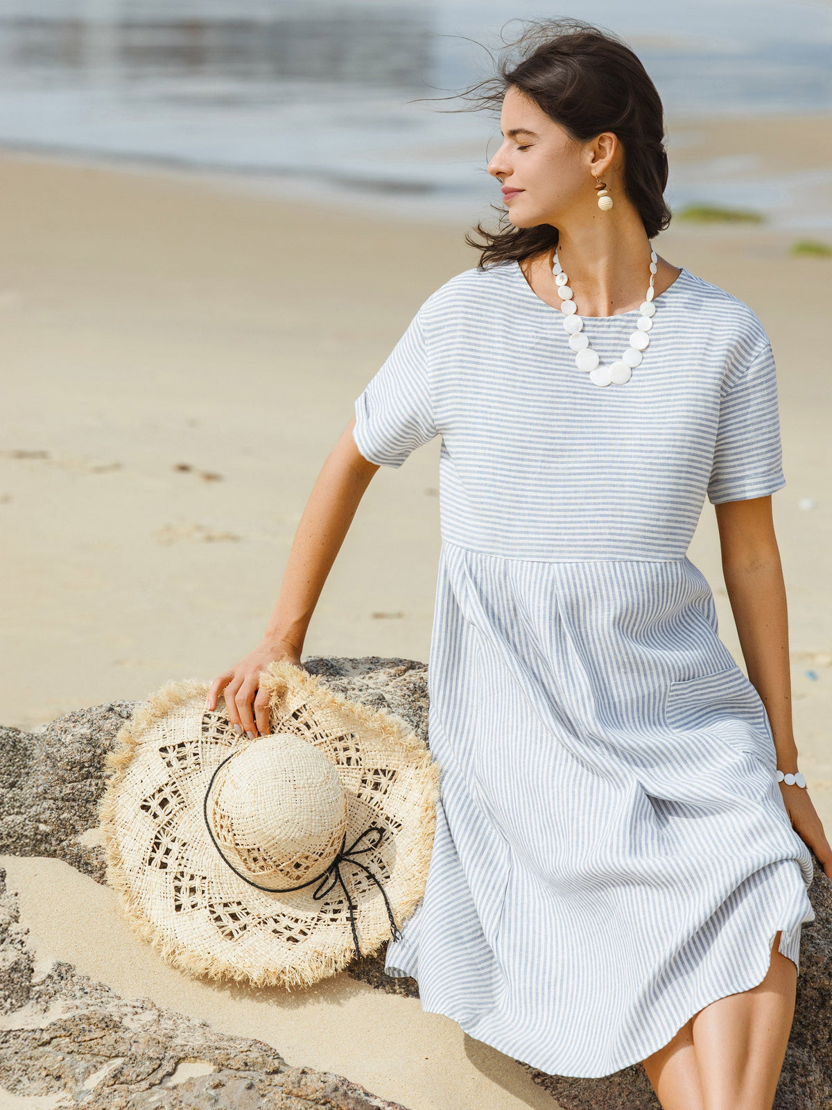 a woman sitting on a rock with a hat