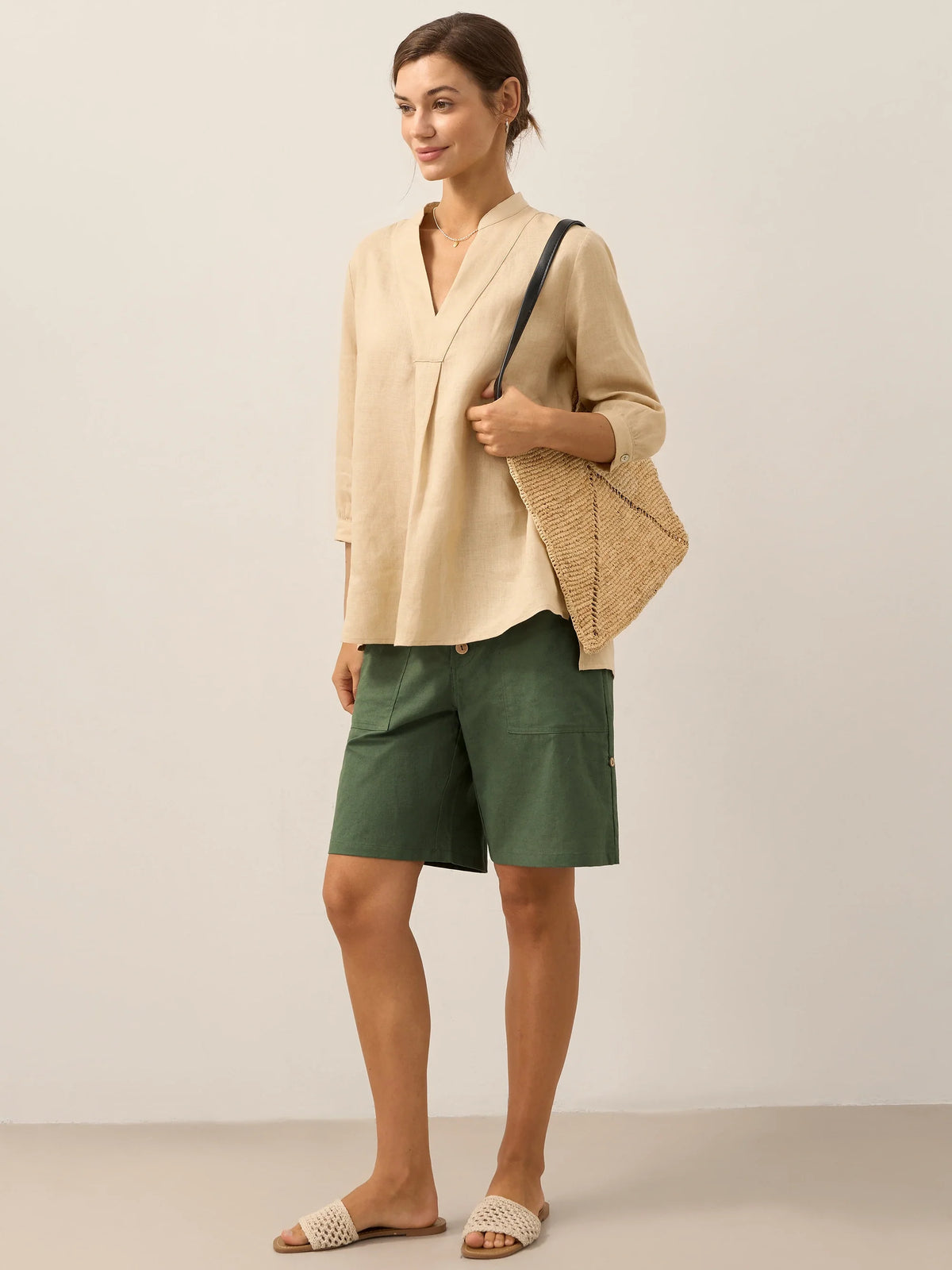 a woman in a beige shirt and green shorts
