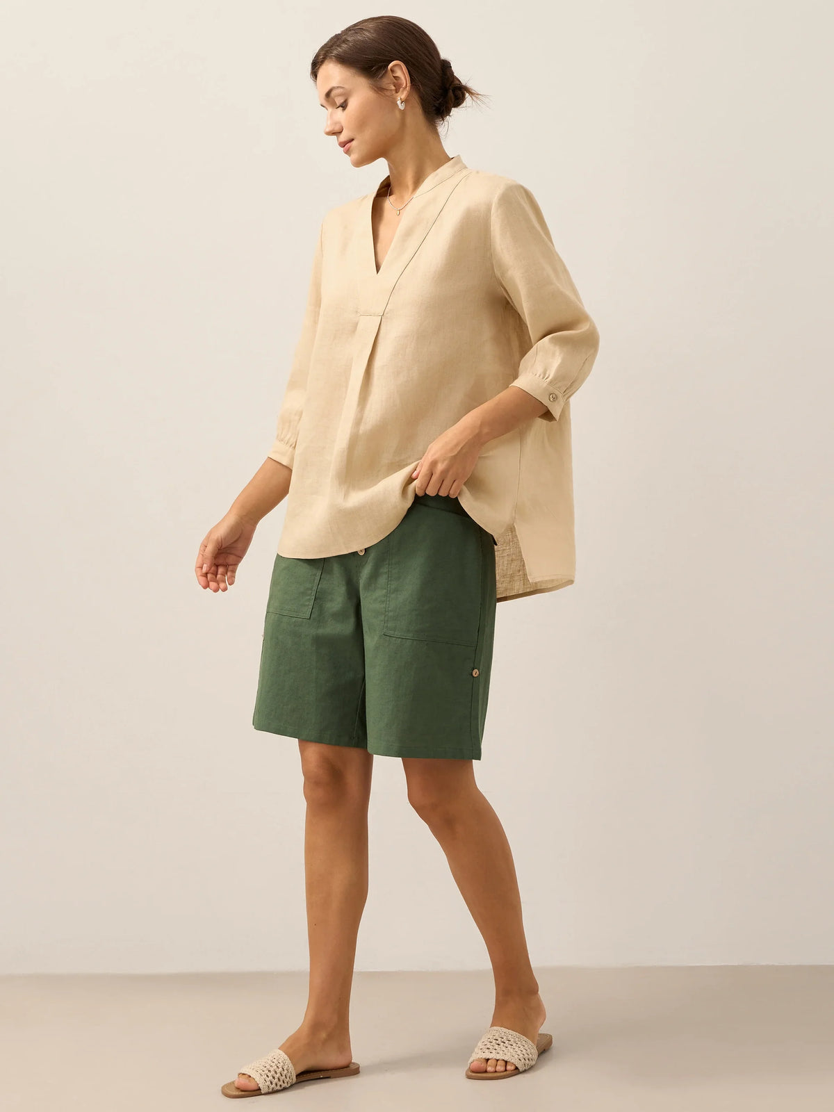 a woman in a beige shirt and green shorts