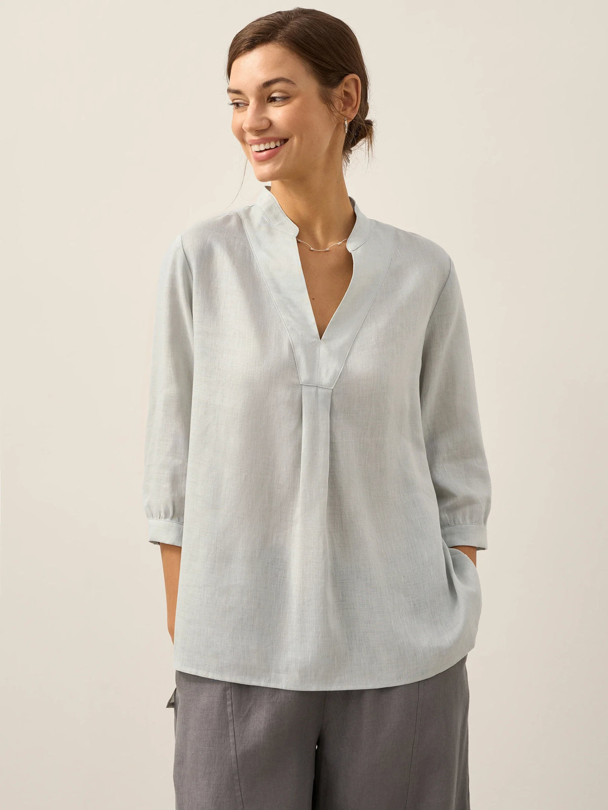 a woman smiling with her hand in her pocket