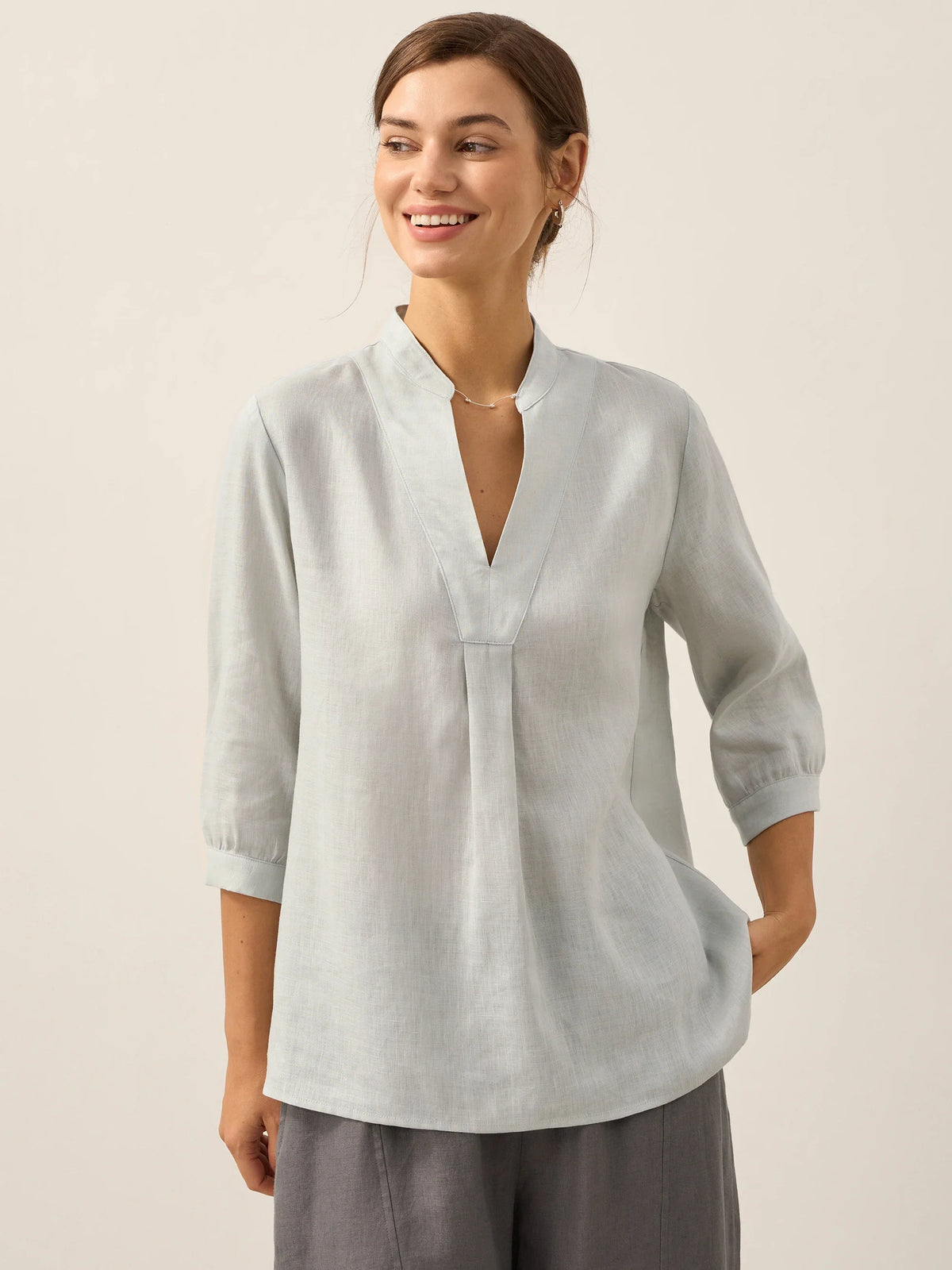 a woman smiling with her hand in her pocket