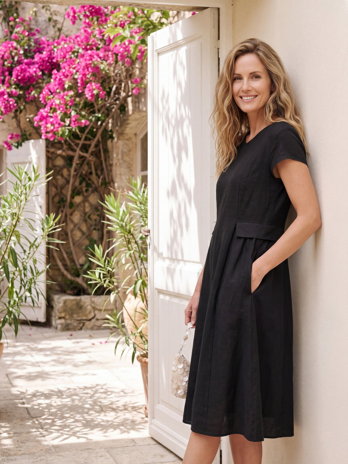 a woman in a black dress leaning against a wall