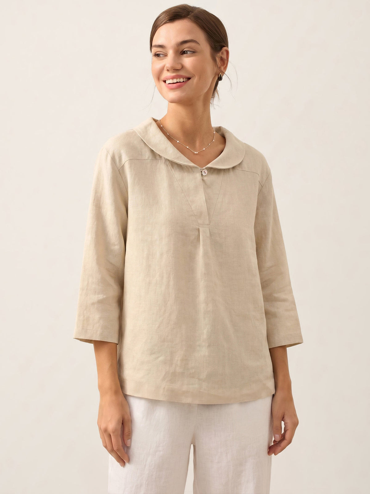 a woman smiling in a beige shirt