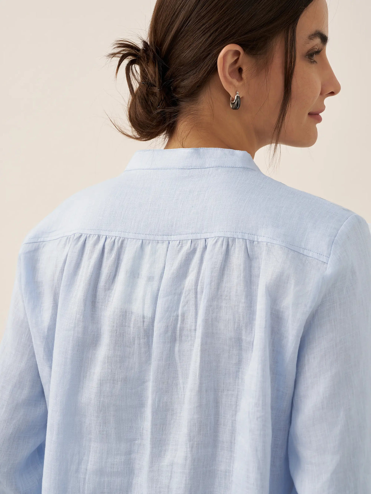 a woman with her hair pulled back in a blue shirt