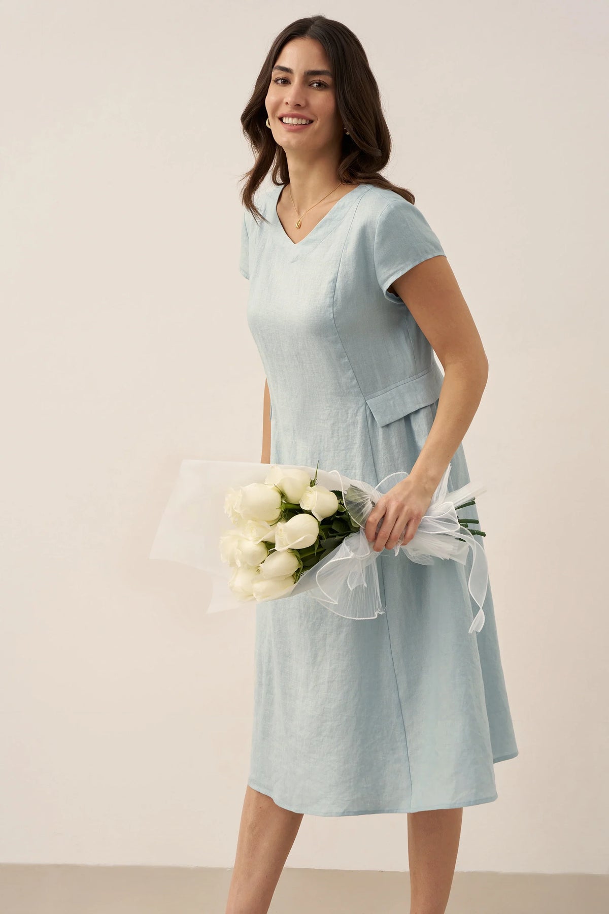 a woman in a blue dress holding a bouquet of white flowers