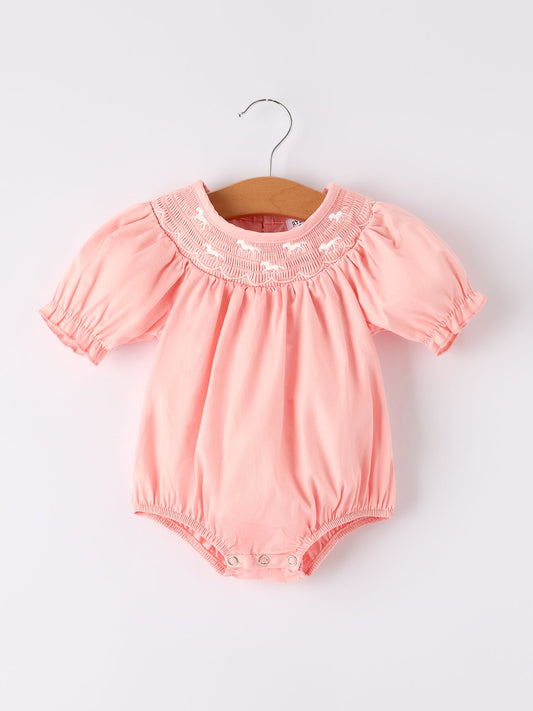 a pink baby romper on a swinger