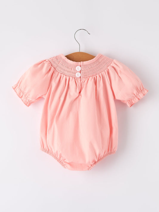 a pink baby romper on a swinger