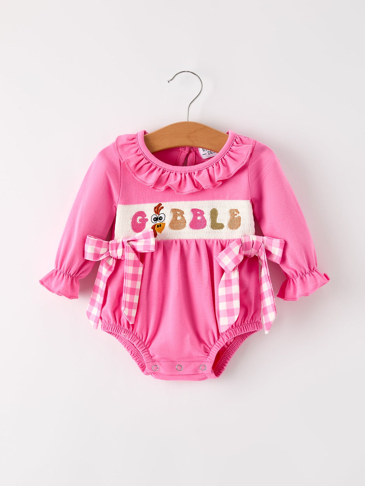 a pink baby romper on a swinger