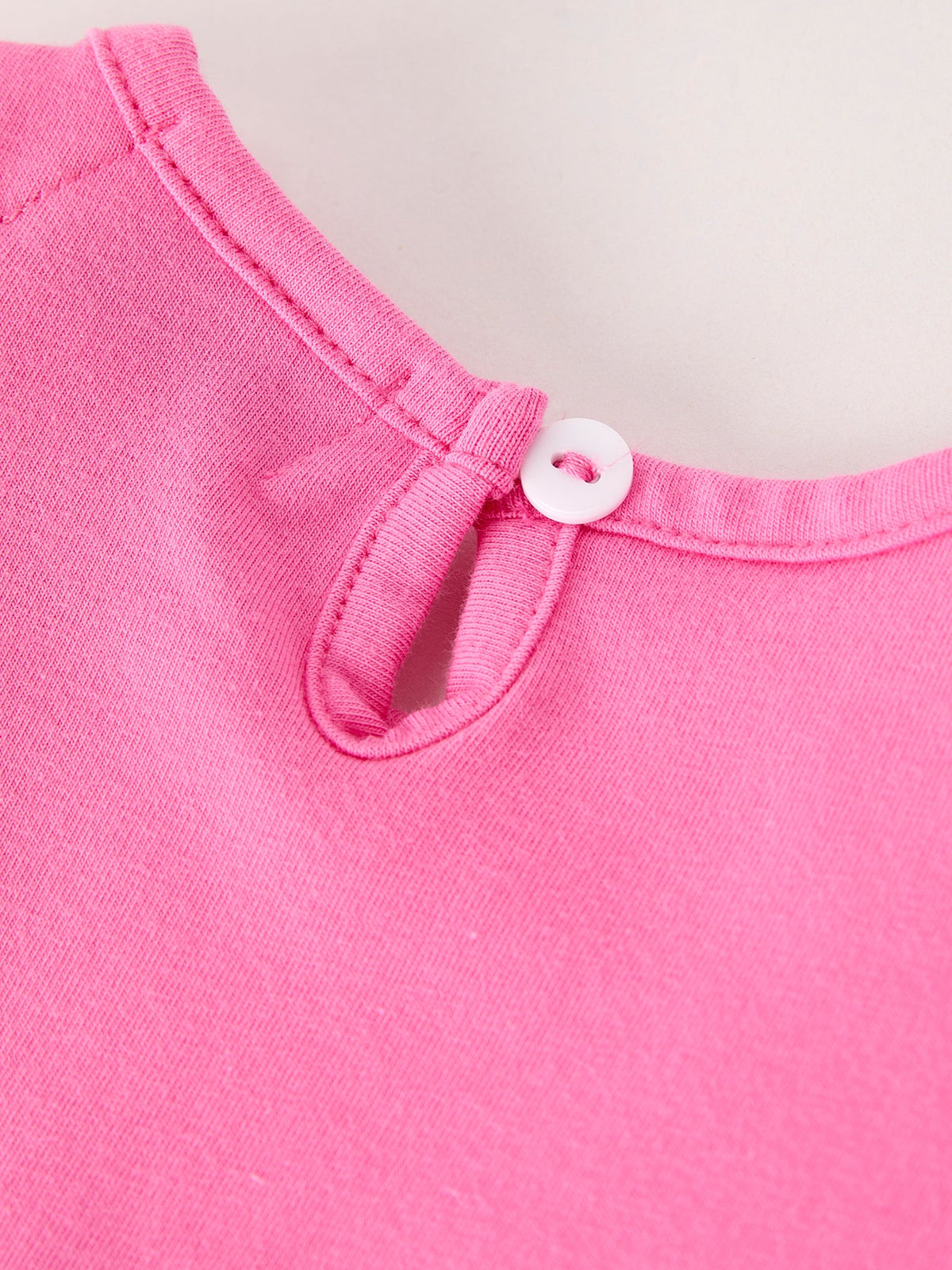 a pink shirt with a white button
