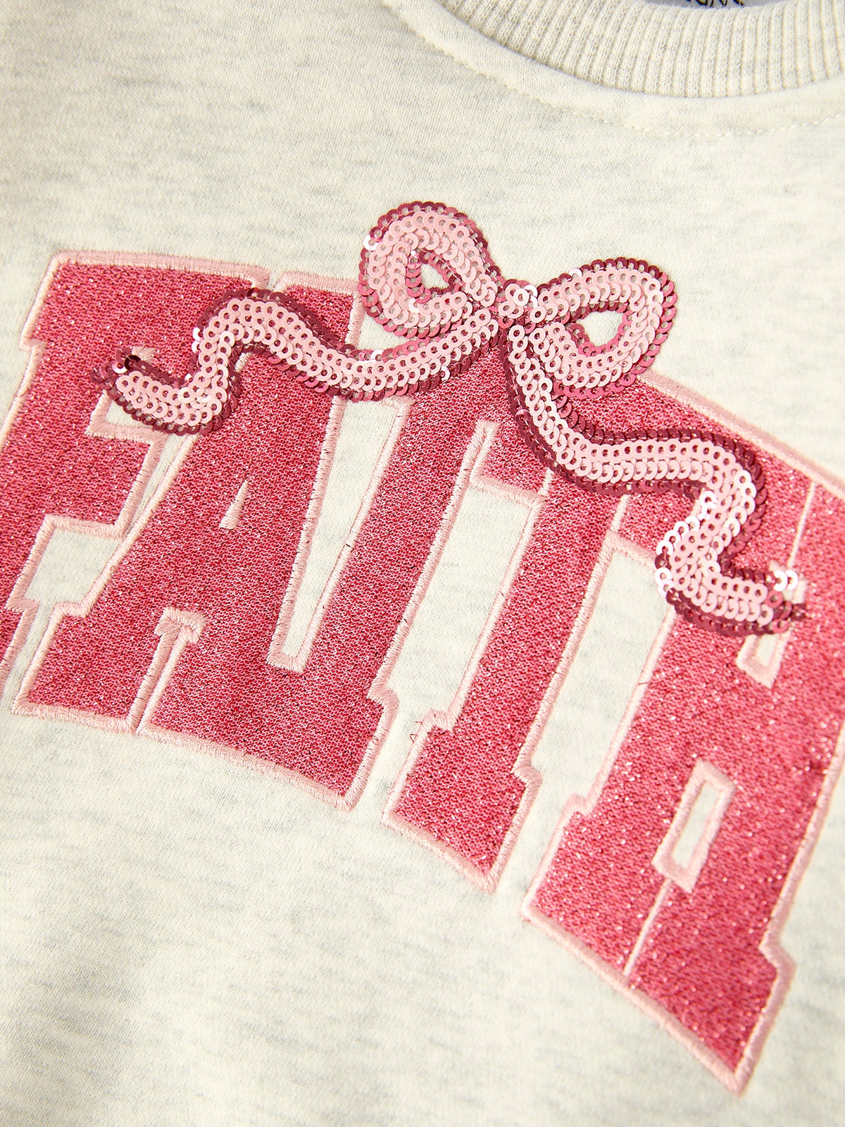 a pink sequined logo on a white shirt